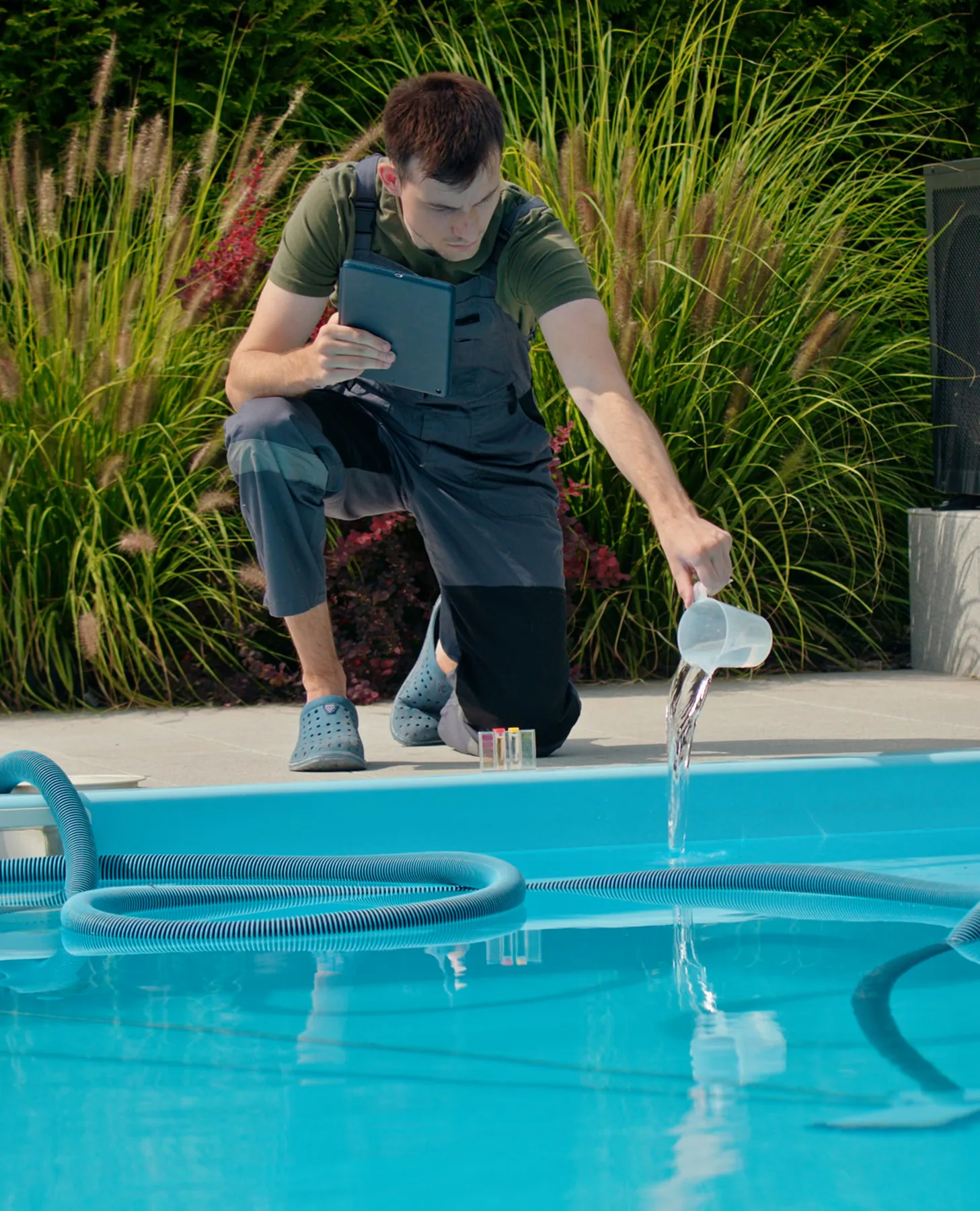 Un technicien Castan analyse l'eau d'une piscine, tablette à la main