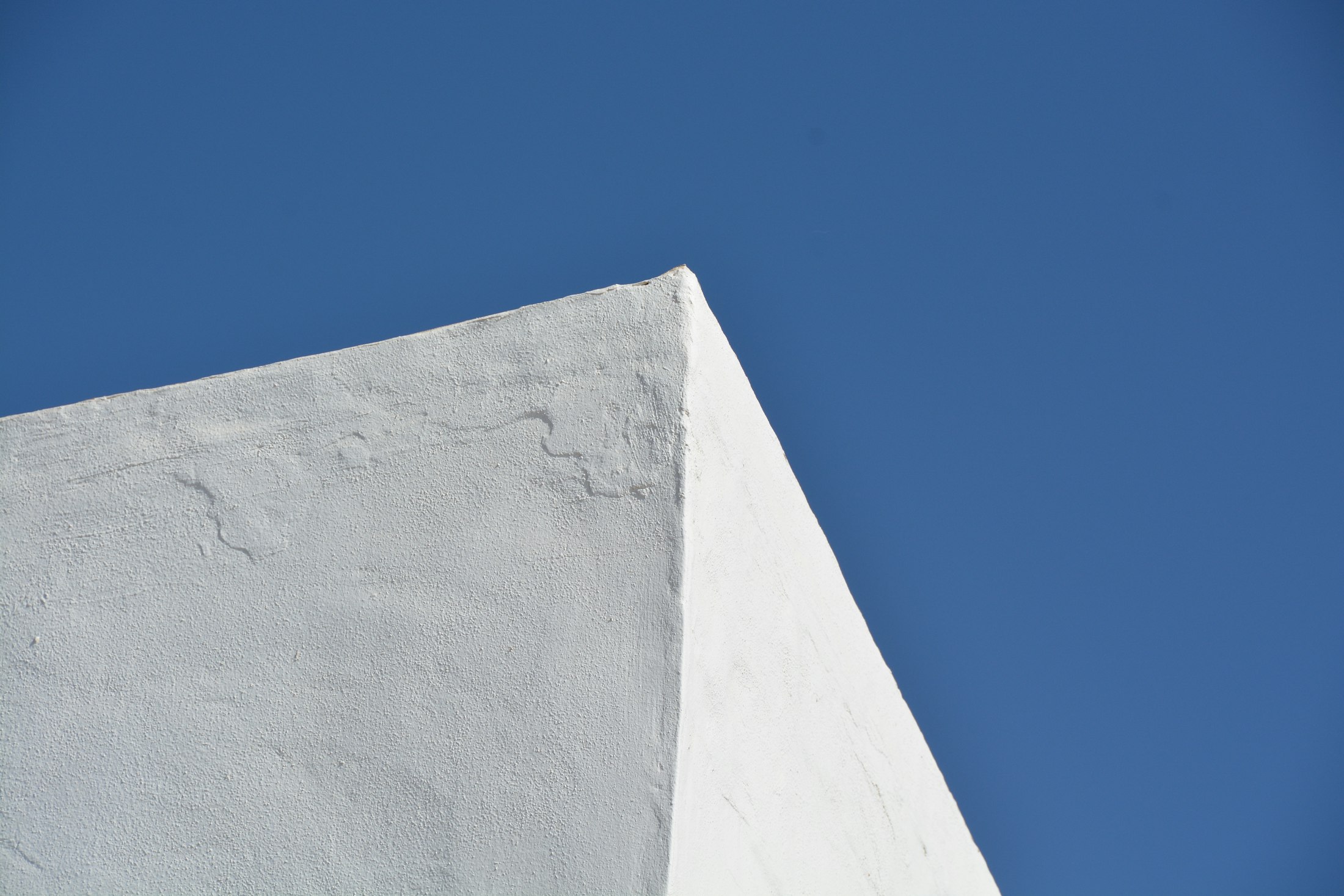 Angle d’un mur blanchi à la chaux sur un ciel bleu profond
