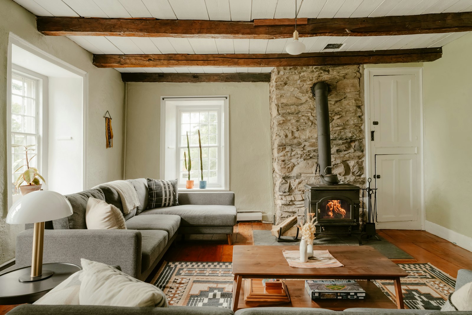 Séjour d’un mas réhabilité : poutres anciennes, cheminée en pierre et mobilier contemporain